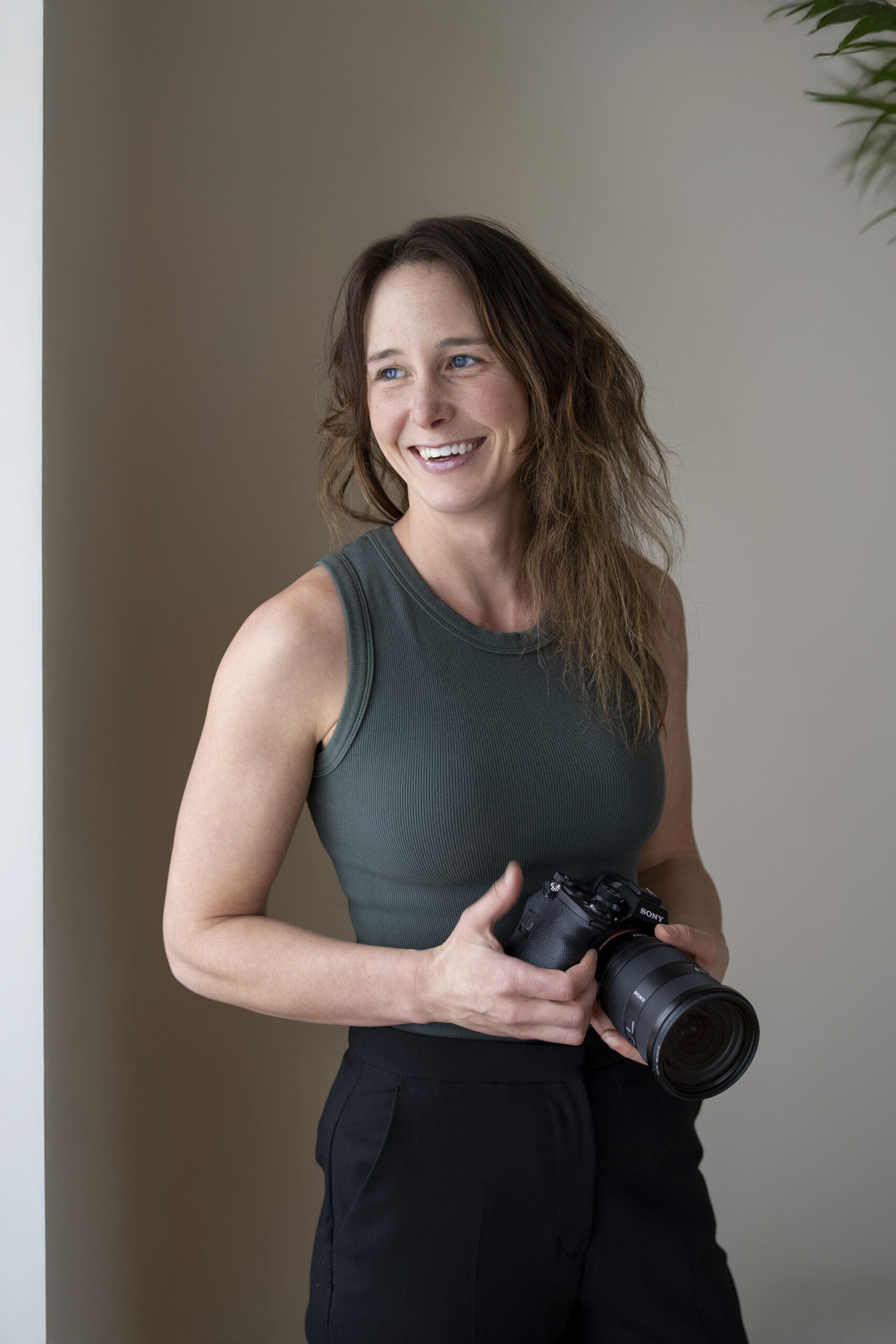 Portrait of Sarah, a professional photographer, holding her camera